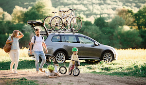 Familj med två barn som tar bilen och cyklar ut på landet